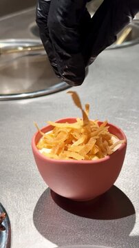 Chef topping a traditional Levantine fatteh dish with crispy fried bread
