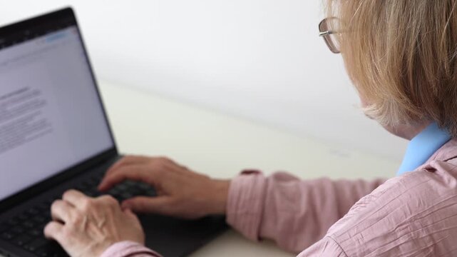 Close up of senior woman hands typing on laptop keyboard at home. Mature woman using computer for online communication, remote work, internet browsing or digital tasks.