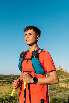 Male trail runner holding trekking poles in nature