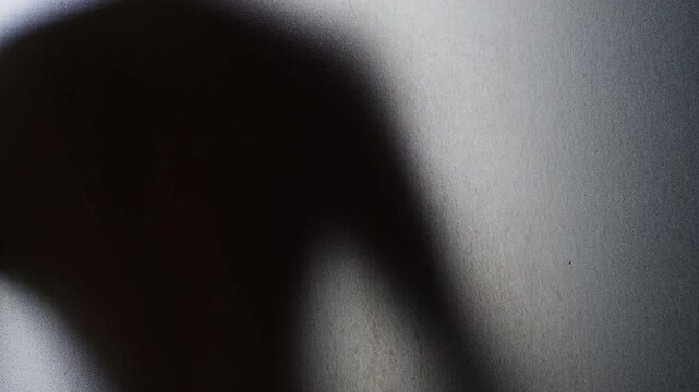 Blurred Human Silhouette Leaning Against Frosted Glass on a Grainy Translucent Surface. Isolation, Fear, Anxiety and Psychological Distress