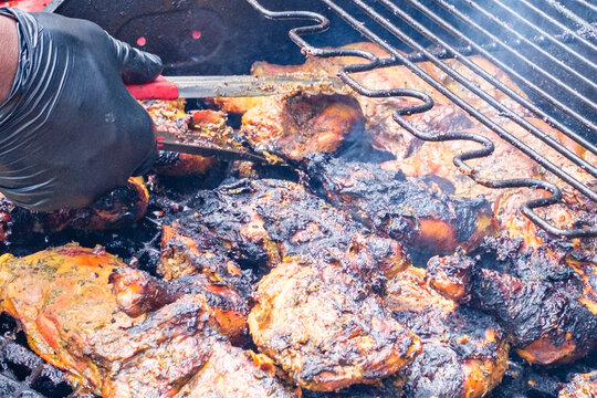 Gloved Hand with Tongs Cooking Chicken on an Outdoor Grill in New Orleans, LA, USA