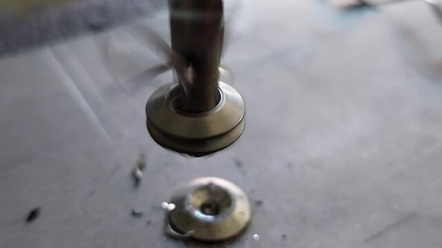 Close-up of a countersink drill bit spinning and cutting a metal washer with metal shavings flying off