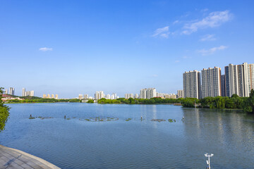 Modern apartment skyline by urban lake under blue sky © LuuDieuThanh