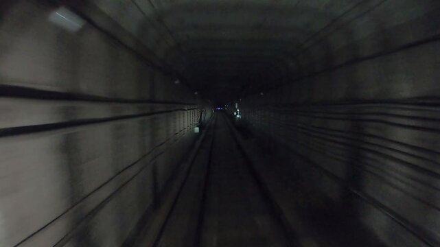 Subway train moving fast at dark tunnel. Speed underground train riding in tunnel. Urban metro driving belowground. Point of view from the railway cabin. Transportation of people concept. Time lapse