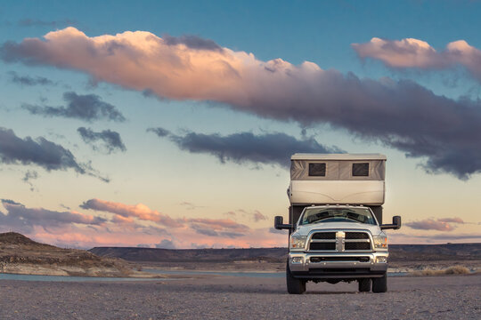 June 15, 2026-New Mexico, US- Truck camper recreational vehicle on a cross country roadtrip parked near a lake with dramatic clouds at sunset.