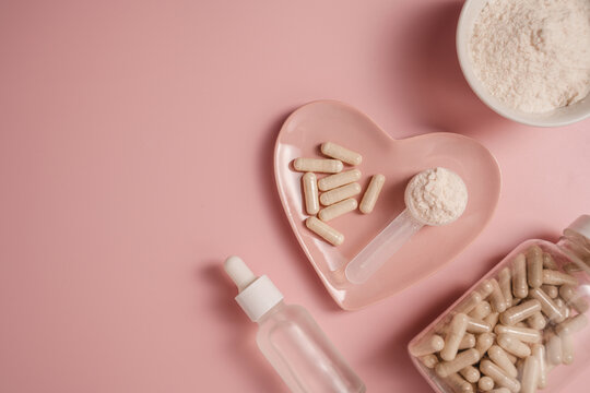 Collagen powder, capsules and serum bottle on pink background, flat lay with copy space