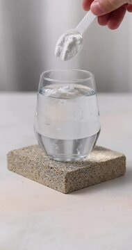 Creatine sport drink. Aminoacid powder in glass on stone background with measuring cup
