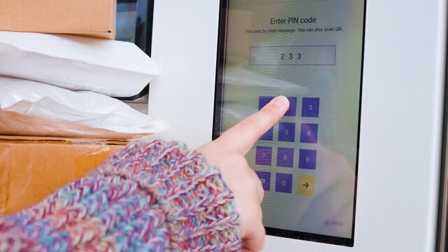 Close-up of a person entering a PIN on a touchscreen at a self-service parcel locker for contactless delivery pickup. E-commerce logistics and modern delivery technology. High quality 4k footage