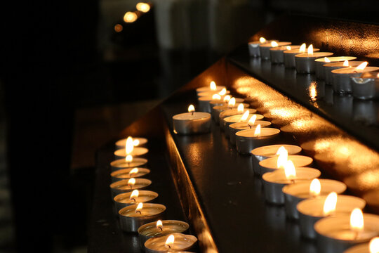 Candele votive accese su un candelabro di metallo all'interno di una chiesa per la preghiera e la devozione spirituale