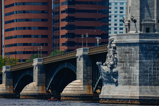 Boston, Massachusetts, United States - 13 June 2025: View of the historic Longfellow Bridge spanning the Charles River with stone arches and decorative carvings near modern red brick buildings.