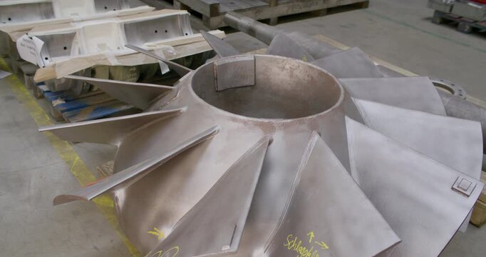 Close up of a large metallic industrial rotor or impeller component on a pallet