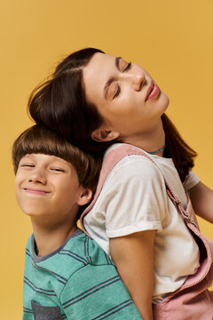 A young mother and her son joyfully lean back against each other in a bright studio.