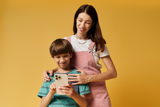 A young mother and her son joyfully bond over a smartphone, reflecting modern parenting.