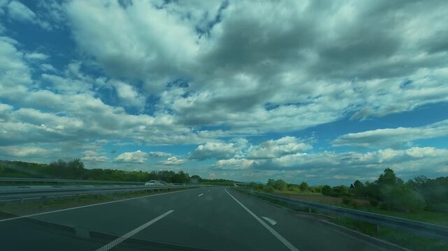 Driving along highway under vast, puffy clouds. Gradac River, Serbia