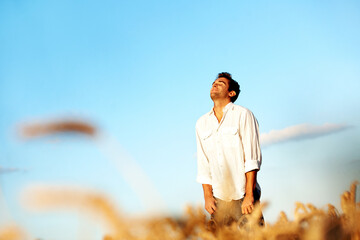 Obraz premium Relax, sunset and travel with man in field for peace, tourist adventure and freedom with space. Wellness, summer vacation and calm with male person in countryside for explore, zen and meadow