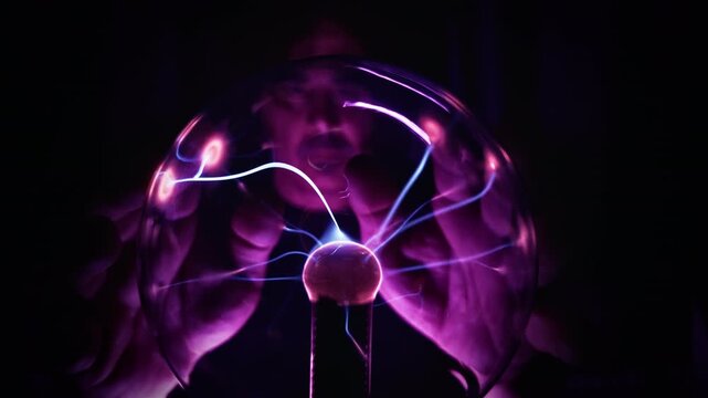 Scientist Observing High Voltage Lightning Discharges Inside Plasma Ball