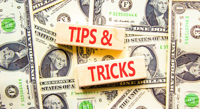 Tips and tricks words symbol. Concept words Tips and tricks on beautiful wooden blocks. Beautiful dollar bills background. Dollar bills. Business tips tricks motivational support concept. Copy space.
