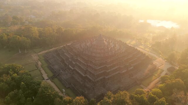 Aerial view of Borobudur Temple at sunrise in Central Java, Indonesia. Ancient Buddhist monument covered in mystical morning mist. UNESCO World Heritage Site, culture, history, and travel themes.
