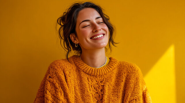 Happy young woman with closed eyes smiling in cozy orange sweater, portrait