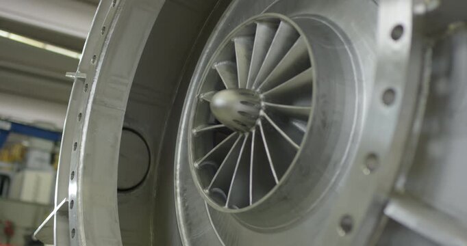 Close up view of a circular turbine or fan impeller with metallic blades inside a machine casing