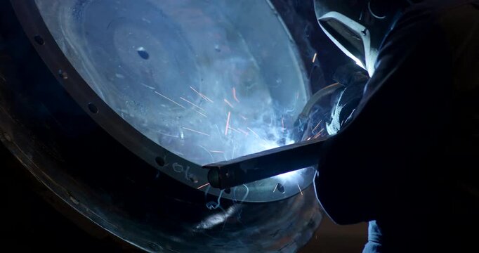 Close up of a worker performing metal welding on a circular industrial component