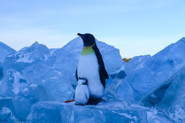 Emperor Penguin Parent and Chick Among Blue Ice in Antarctica © ThaiKhanh