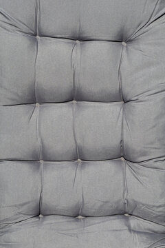 Gray tufted upholstered cushion surface with stitched square textile pattern