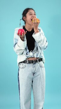 Teenage girl choosing between fresh apple and burger