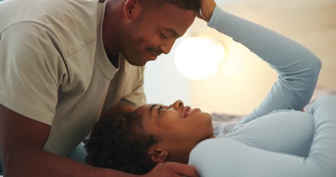 Love, black couple and kiss forehead in bedroom with connection, happy and loyalty together at home. Smile, man and woman in bed with romance for support, trust and relationship security with partner