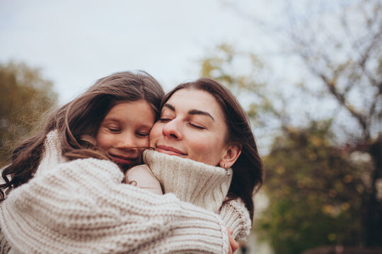 Tender close-up of mother and daughter embracing outdoors in autumn. Unconditional love, maternal bonding, family warmth, and emotional closeness.  Mother's day.