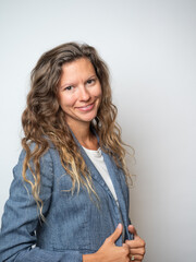 Obraz premium Confident professional woman standing against a neutral background, smiling at the camera in business casual attire. Ideal for concepts related to leadership, entrepreneurship, small business
