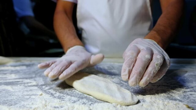 Prepared pide dough is being shaped and patterned on a floured work surface before baking. Bakery preparation, handmade dough process, food production and professional kitchen workflow concept.