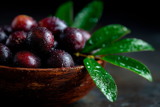 Fresh Jamun Fruit in a Wooden Bowl with Green Leaves and Water Droplets