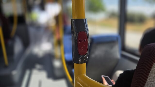 Close-up of red stop button on yellow pole inside madrid public bus for transport background and urban transit banner and commuter design