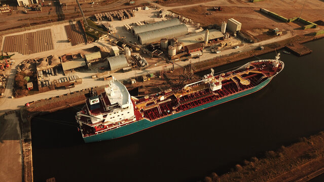 Aerial view of a large tanker ship moored at the Cardiff Docks, surrounded by industrial buildings and warehouses in Cardiff, Wales, United Kingdom.
