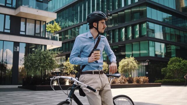 Man drinks coffee leaning on bicycle in glass office courtyard