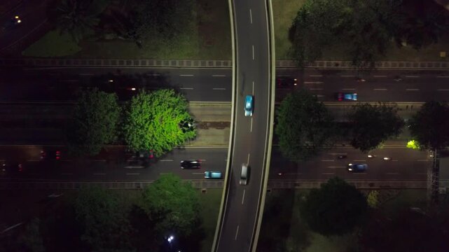 Semanggi Interchange at night, with dense red light trails tracing the curve of the ramps against the dark cityscape.