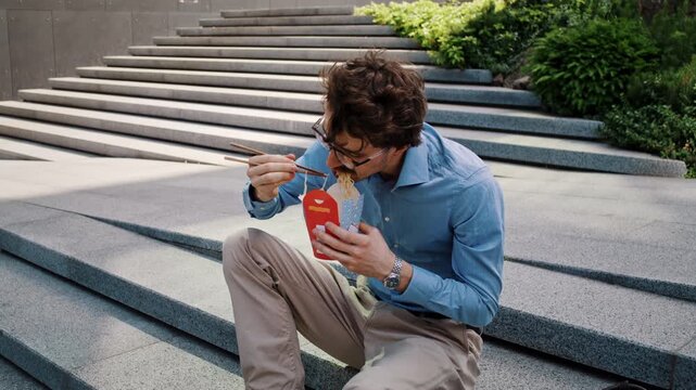 Man takes quick lunch break on sunny office plaza steps