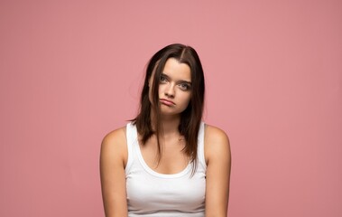 Fototapeta premium Young woman looking with a bored and tired expression, showing disinterest and apathy in a studio portrait