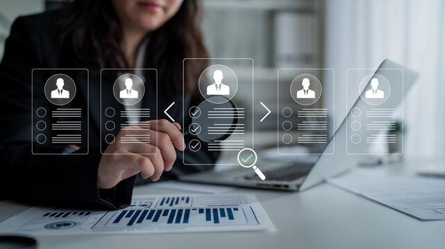 Professional Businesswoman Reviewing Resumes and Analyzing Data in Modern Office Environment with Graphs and Charts Displayed on a Laptop Screen. Glyphic.