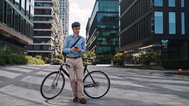 Man looks around standing near bicycle in modern office plaza 
