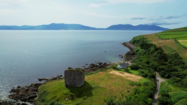 Drone aerial 4k ultra high definition footage of historic ruins of minard castle on lush green cliffside overlooking calm sea Dingle peninsula ireland