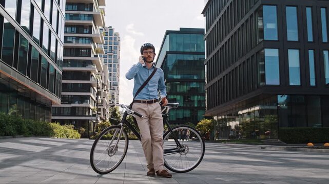 Man makes phone call leaning on bicycle in spacious office plaza