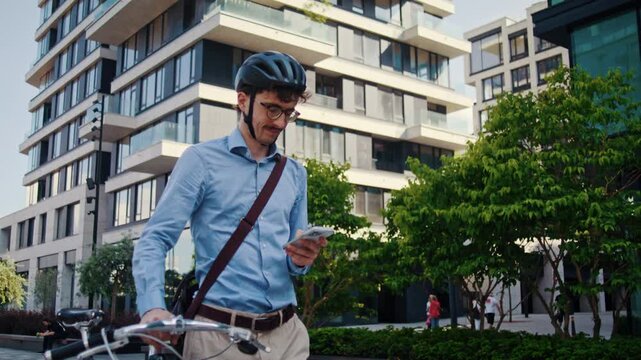 Man checks smartphone while guiding bicycle through plaza