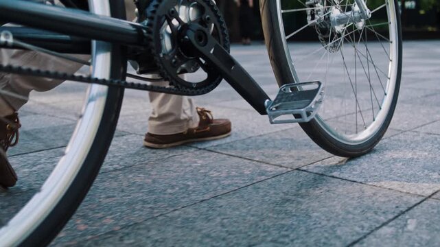 Man walks bicycle across paved office plaza close low angle view