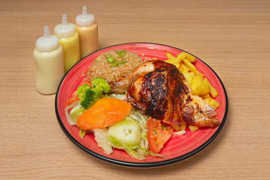 A hearty Peruvian "mostrito" served on a white platter, showcasing the broasted chicken coated in a mustard and spice marinade