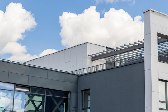 Modern commercial building facade with grey panels, glass windows, and blue sky reflection, Urban