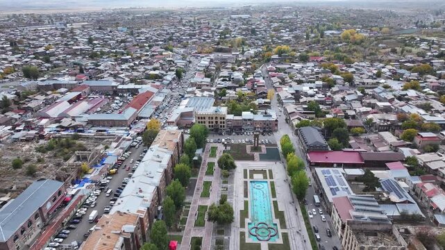 Aerial drone shot of the beautiful city of Gyumri in Armenia, showcasing its historic architecture, busy city squares, streets, and the famous landmark Holy Saviour's Church during autumn.

