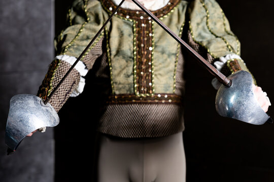 Fencer in vintage historical costume holding crossed rapiers swords from Don Quixote performance