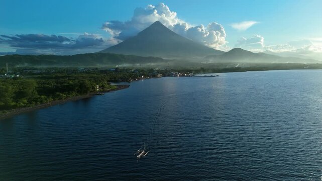Drone footage of Mayon Volcano in Albay, Philippines. Tropical coastline with boat crossing the bay. Ideal for travel and destination marketing projects.